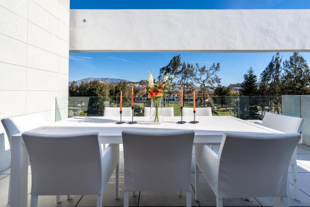 a white dining room table with white chairs and a large window at Holiday Apartment Navigolf La Cala in La Cala de Mijas