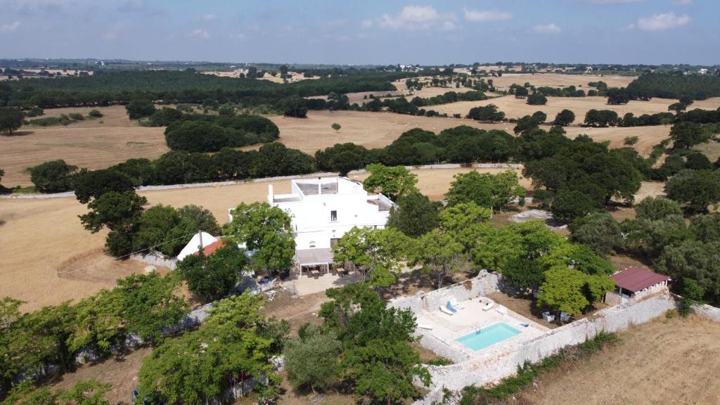  Elle offre une vue aérienne sur une grande maison blanche dotée d'une piscine. dans l'établissement B&B Masseria Santanna, à Monopoli
