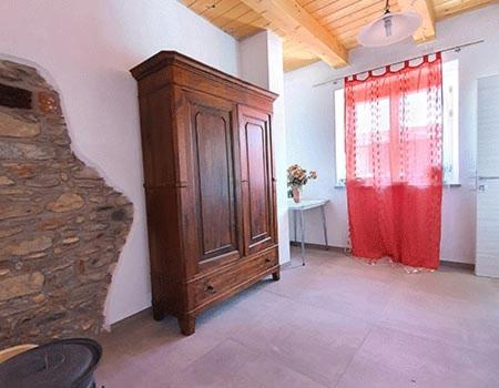 Habitación con armario de madera y cortina roja. en Cascina la Demilana, en Bibiana