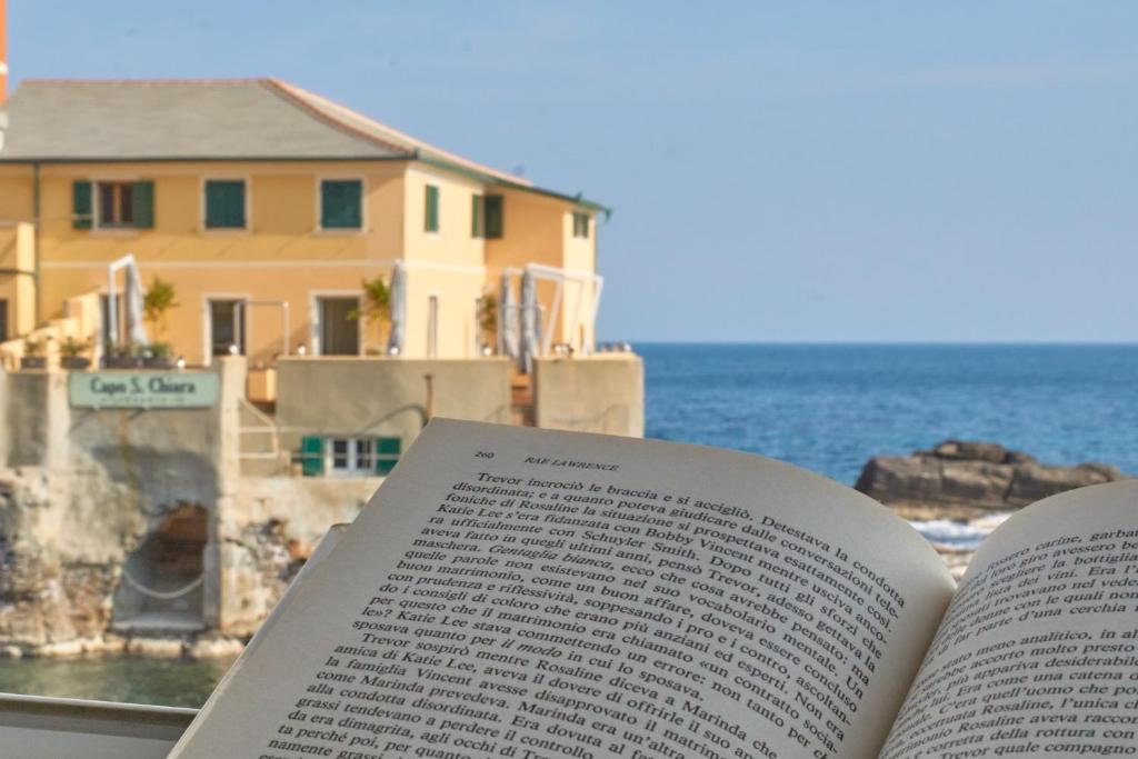 un libro abierto sentado en una mesa junto al océano en Baiàn Casa Vacanze en Génova