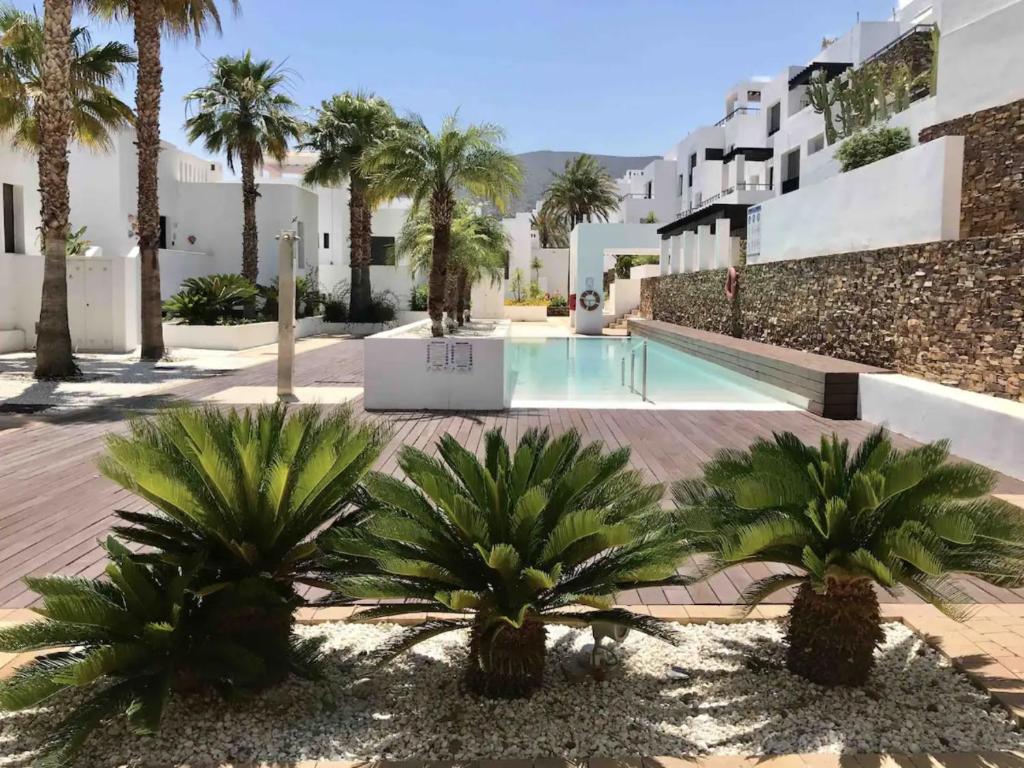 a view of a swimming pool with palm trees and buildings at Casa Indalo - Resort Macenas Mojacar in Mojácar