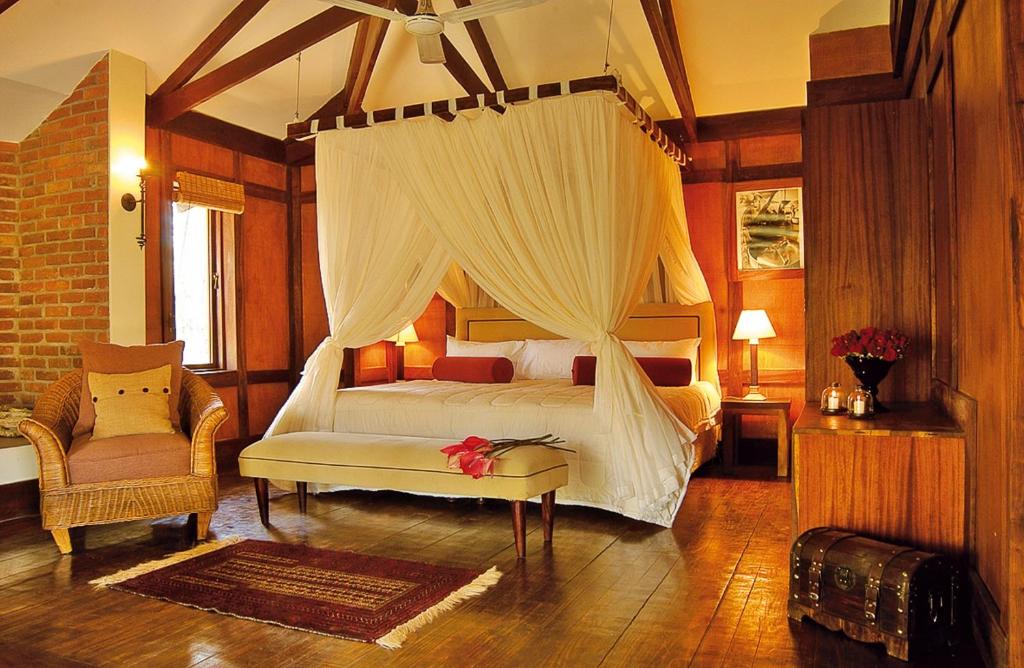 een slaapkamer met een hemelbed en een stoel bij Elewana Arusha Coffee Lodge in Arusha