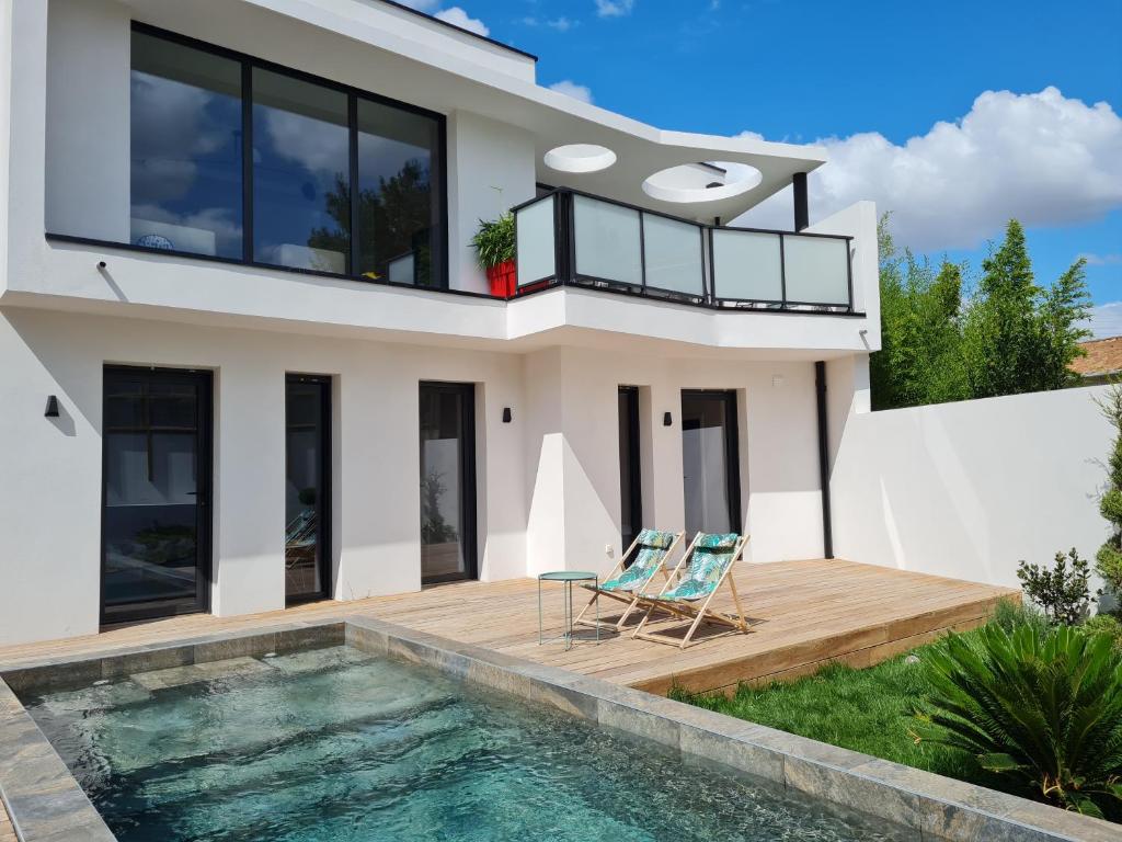 a house with a swimming pool and two chairs on a deck at Villa NC30 , chambres privatives deluxe in La Rochelle
