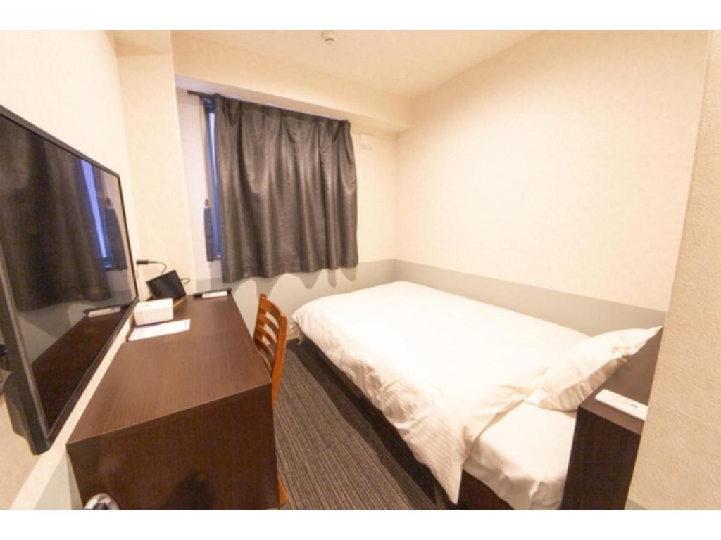Habitación de hotel con cama, escritorio y TV. en Hotel Taiyonoen Tokushima Kenchomae - Vacation STAY 26339v en Tokushima