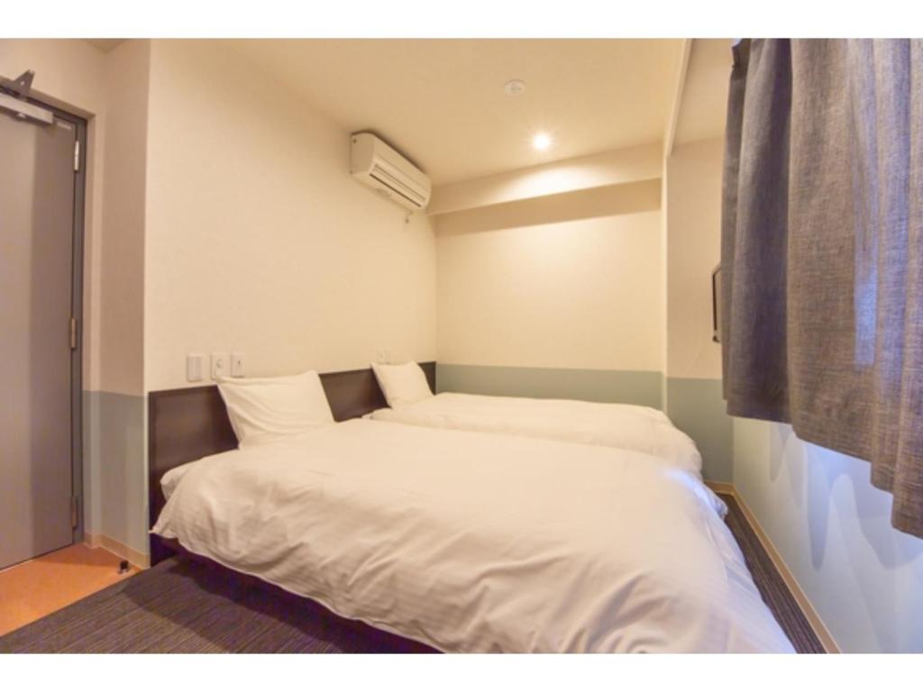 ein kleines Schlafzimmer mit zwei Betten darin in der Unterkunft Hotel Taiyonoen Tokushima Kenchomae - Vacation STAY 26347v in Tokushima