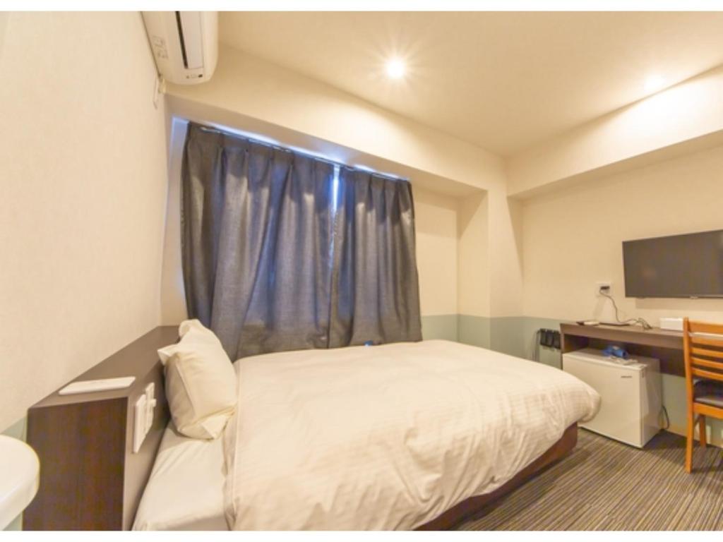 een slaapkamer met een bed, een bureau en een raam bij Hotel Taiyonoen Tokushima Kenchomae - Vacation STAY 26340v in Tokushima