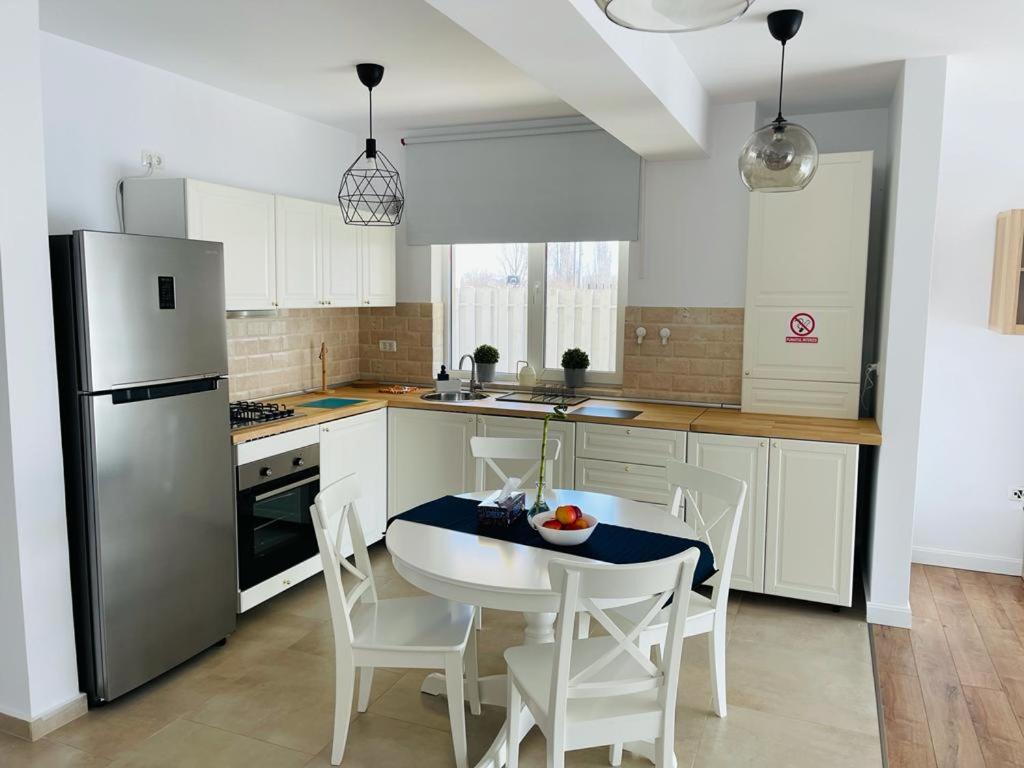 La cuisine est équipée d'une table, de chaises et d'un réfrigérateur. dans l'établissement Galaxy Residence Villa, à Otopeni