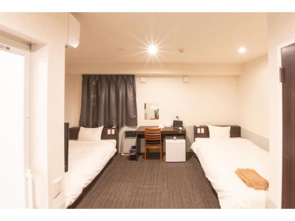 una camera d'albergo con 2 letti e una scrivania di Hotel Taiyonoen Tokushima Kenchomae - Vacation STAY 26355v a Tokushima