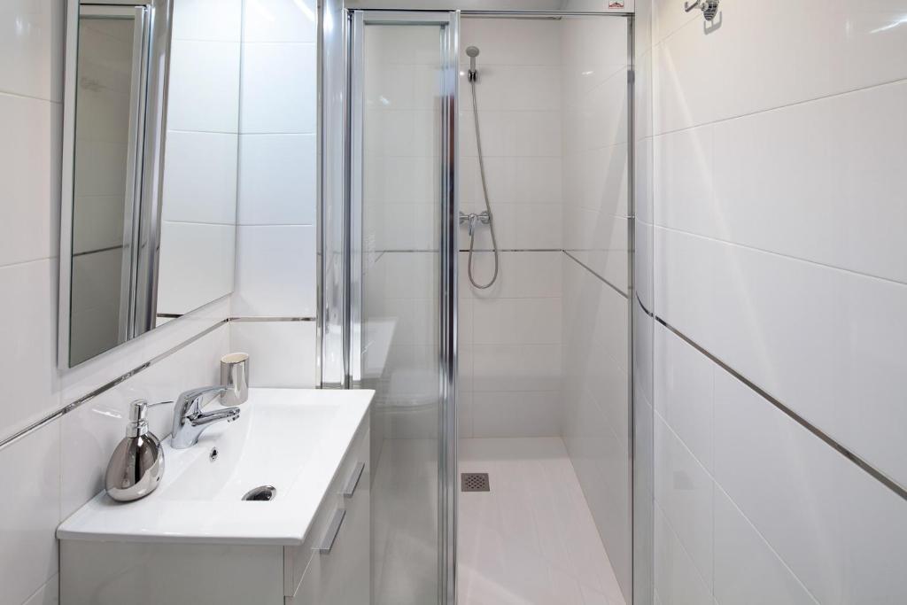 biała łazienka z prysznicem i umywalką w obiekcie Wanderlust Malaga Apartamentos 3 w Maladze