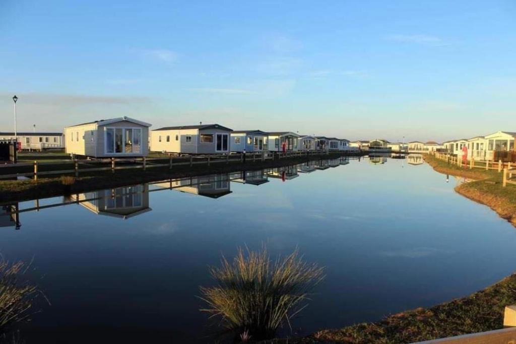 a row of mobile homes next to a body of water at The Blue Beachcomber in Chapel Saint Leonards