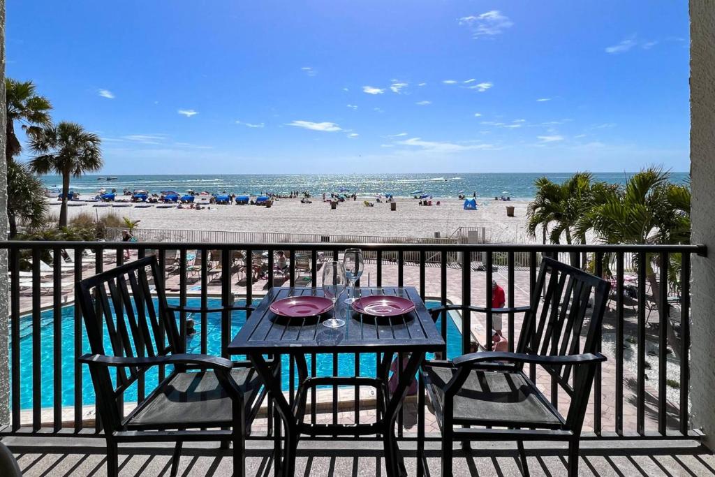 a table and chairs on a balcony with the beach at 103 - Sandy Shores in St Pete Beach