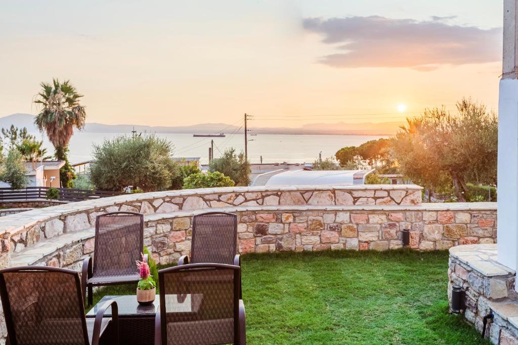 a patio with chairs and a stone wall and the ocean at Kelly's Sunset Apartment 1 Κalamata in Almirón