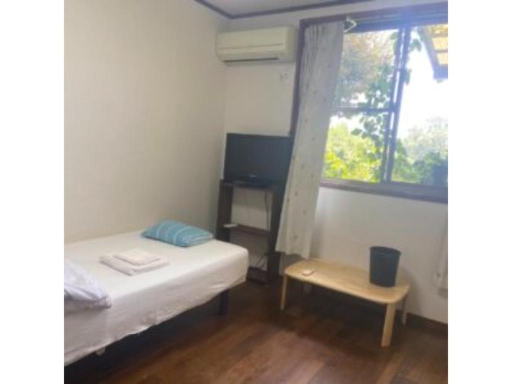 um pequeno quarto com uma cama e uma janela em Asobiyahouse Iki - Vacation STAY 30422v em Iki