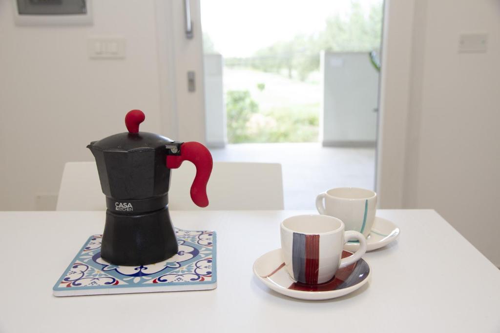 una cafetera negra y dos tazas en una mesa en Casa Raineri, en Paceco