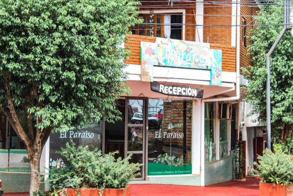 a store on a street with trees in front of it at El Paraiso Apart Hotel in Puerto Iguazú