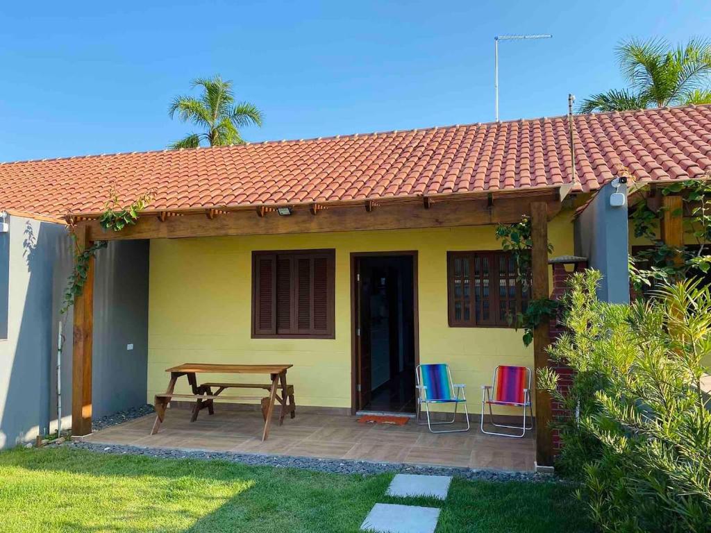 une petite maison jaune avec une table et des chaises en bois dans l'établissement Casinhas Terõ -, à São Sebastião