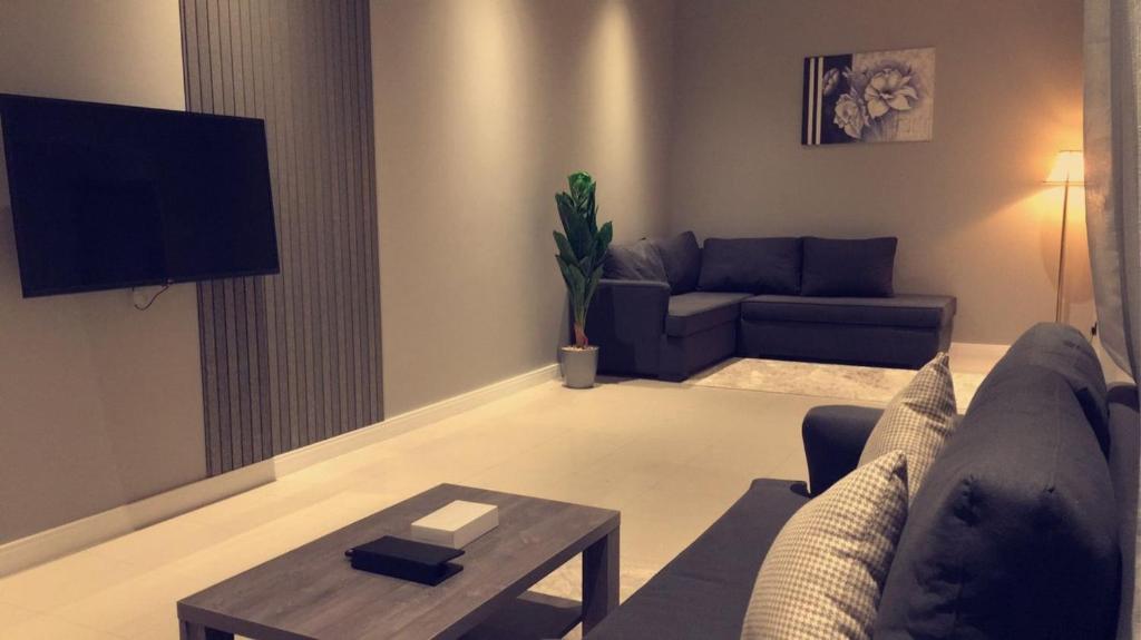 Voyage Apartments في الرياض: غرفة معيشة مع أريكة وطاولة