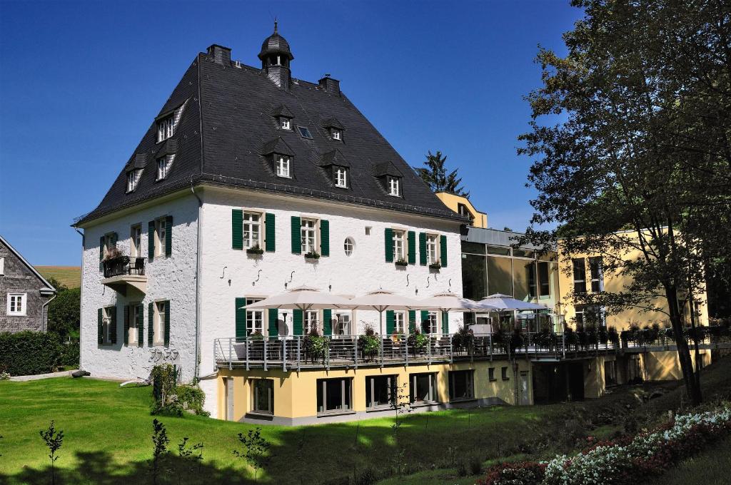 ein großes weißes Gebäude mit schwarzem Dach in der Unterkunft Hotel Gut Landscheid in Burscheid