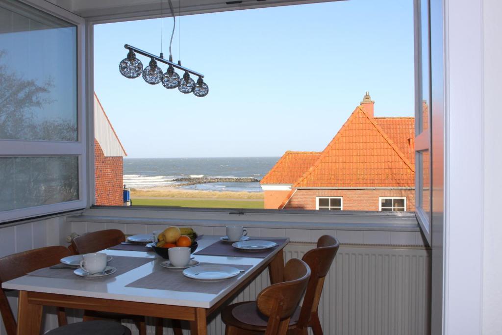 einen Esstisch mit Stühlen und ein großes Fenster in der Unterkunft Ferienwohnung Ostseeglück, Schönberger Strand, Meerblick in Stakendorfer Strand
