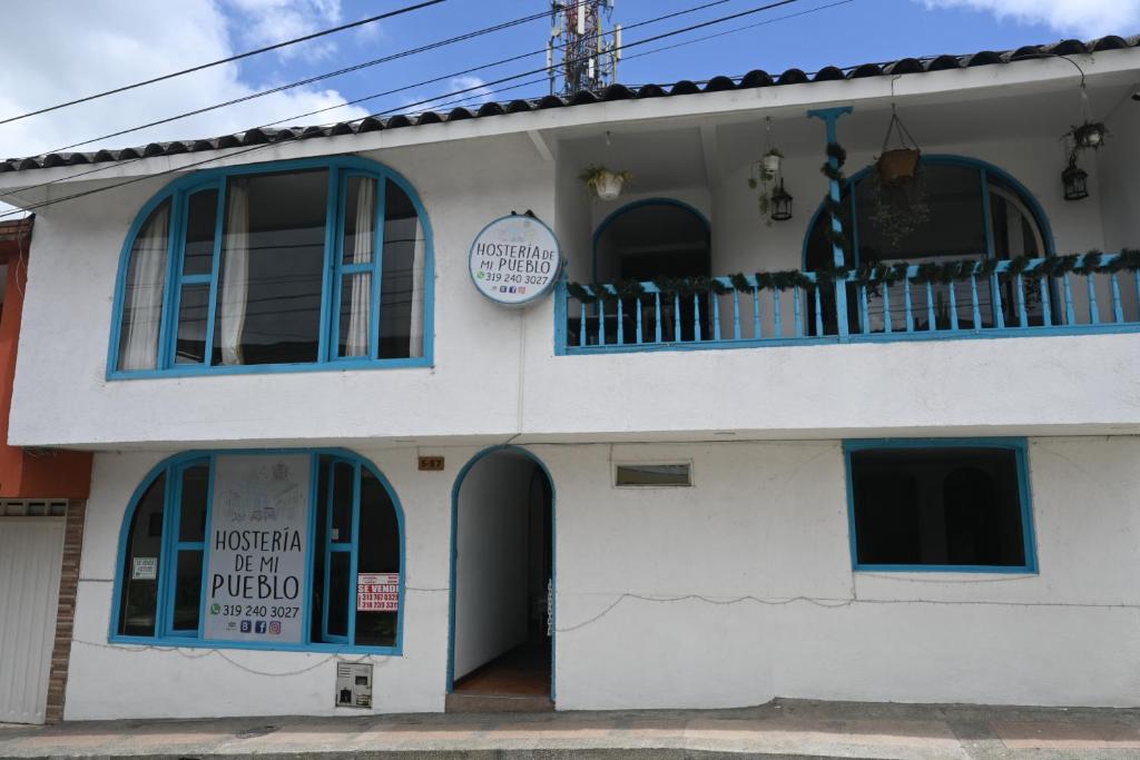 Edificio blanco con ventanas azules y balcón en Hosteria De Mi Pueblo, en Filandia