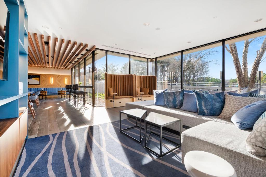 a living room with a couch and tables and windows at Sheraton Chapel Hill in Chapel Hill