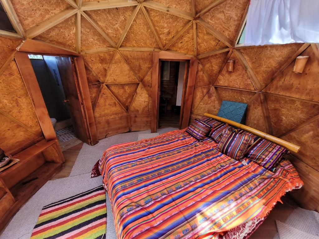 een uitzicht op een bed in een houten kamer bij Glamping Paraiso de Tausa in Tausa Viejo