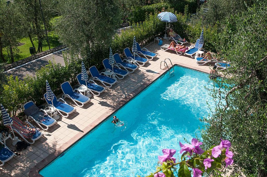 an overhead view of a swimming pool with lounge chairs and a person swimming at Hotel Garden in Limone sul Garda