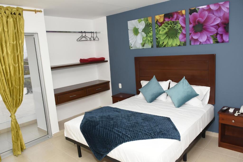 1 dormitorio con 1 cama con paredes azules y espejo en Hotel Kai Soledad Atlántico, en Soledad