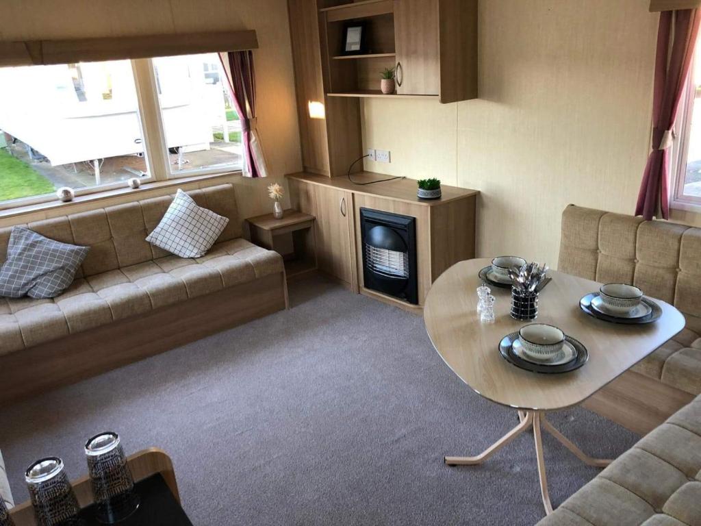 a living room with a table and a couch at Evans Whitehouse Caravan Towyn in Abergele