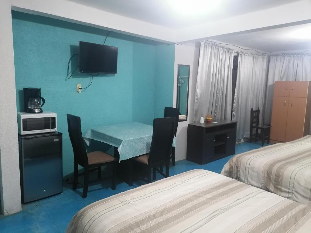 Habitación de hotel con mesa y TV en la pared en Hospedaje La Cienega en Zacatlán