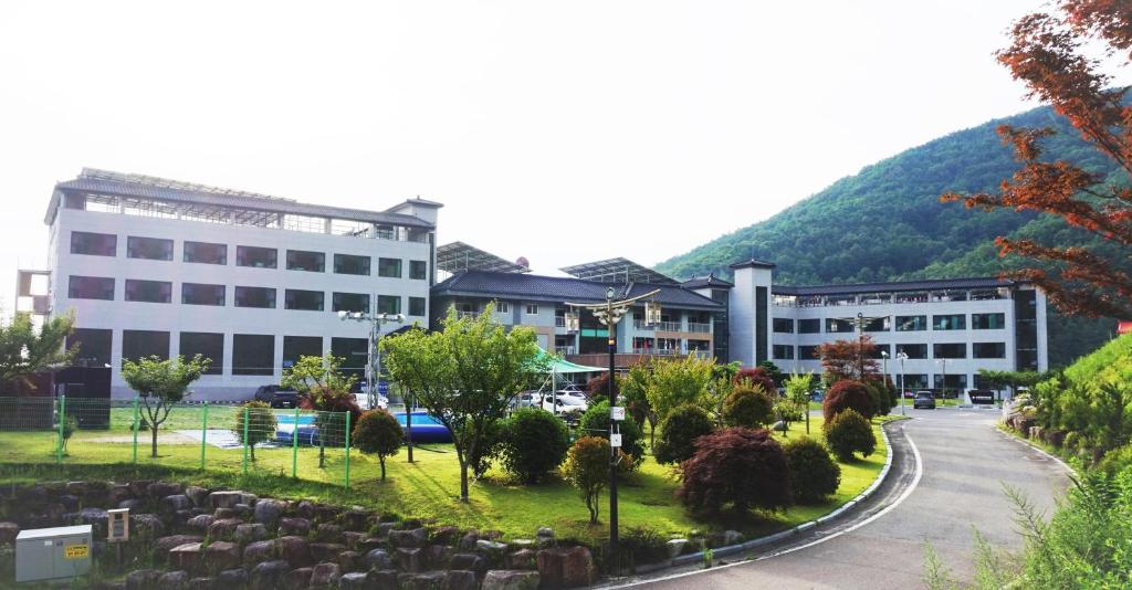 a building with a cemetery in front of a mountain at Sancheong Korean Medicine Family Hotel in Sancheong
