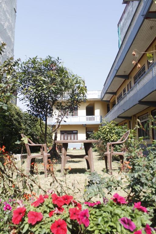 due panche e fiori di fronte a un edificio di Pushpa Guest House a Pokhara
