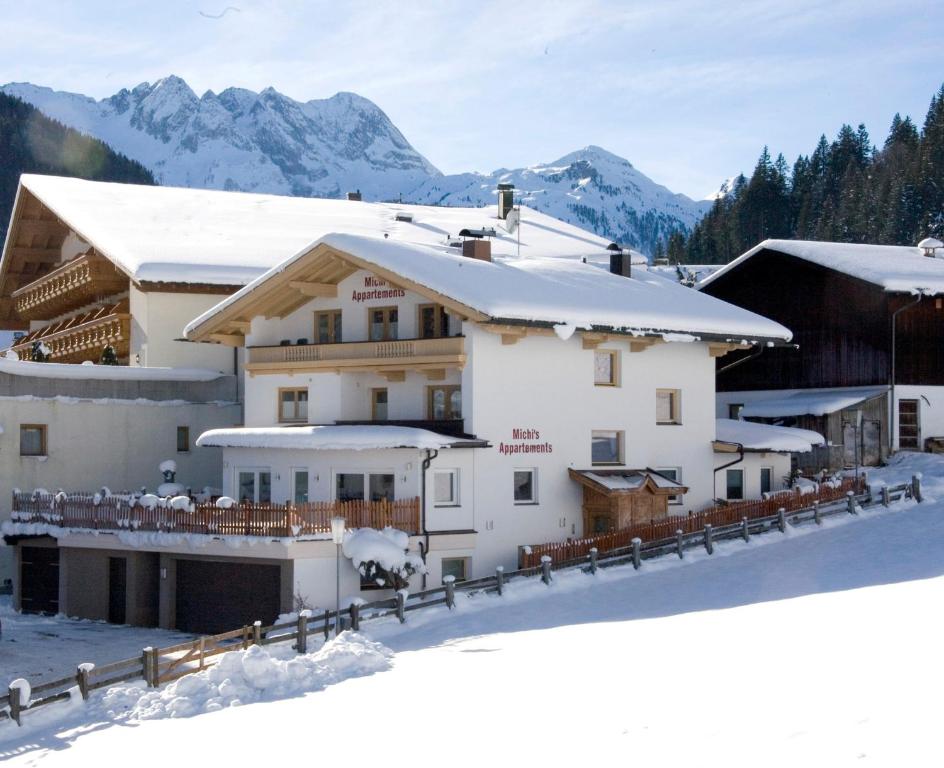 a hotel in the snow with mountains in the background at Michi's Appartements in Gerlos