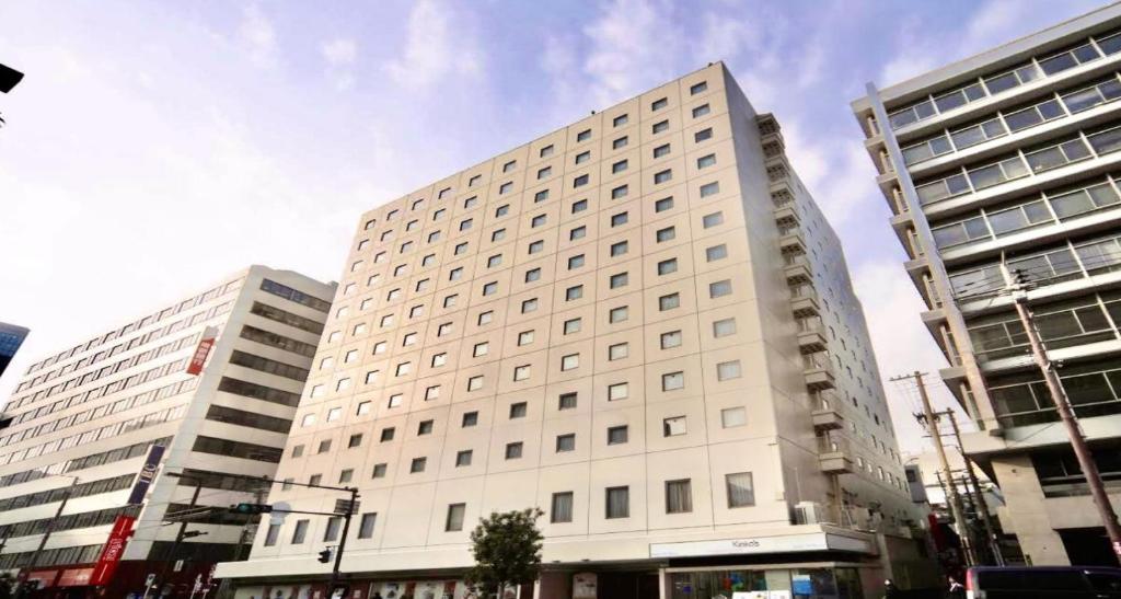ein großes weißes Gebäude in einer Stadt mit zwei hohen Gebäuden in der Unterkunft Osaka Tokyu REI Hotel in Osaka
