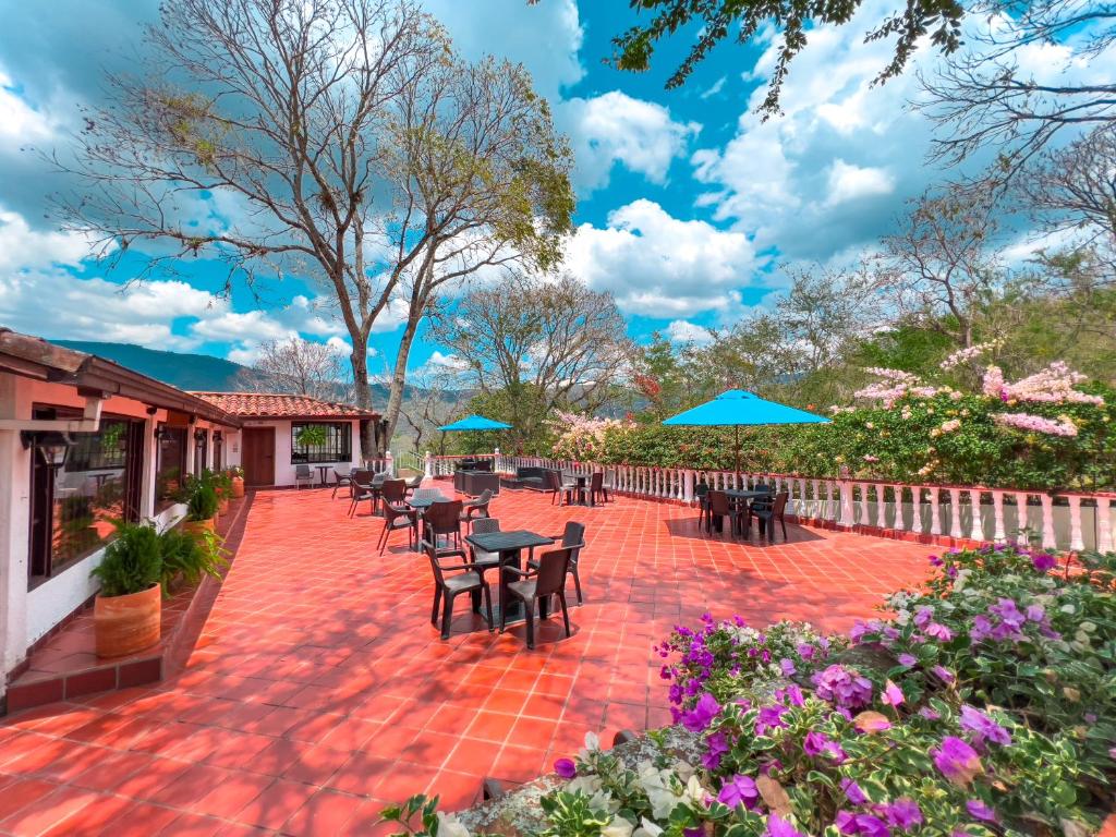 a patio with tables and chairs and blue umbrellas at Hotel Campestre La Trinidad in San Gil