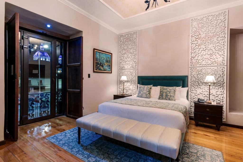 a bedroom with a bed with a bench in it at Hotel La Cofradía Pub-House in Cuenca
