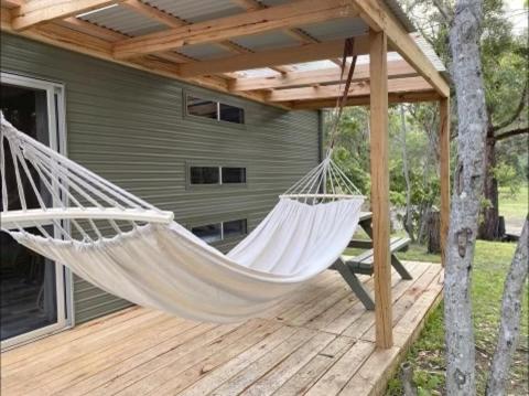 a hammock hanging from a pergola on a deck at Tathra Beach Eco Camp in Tathra