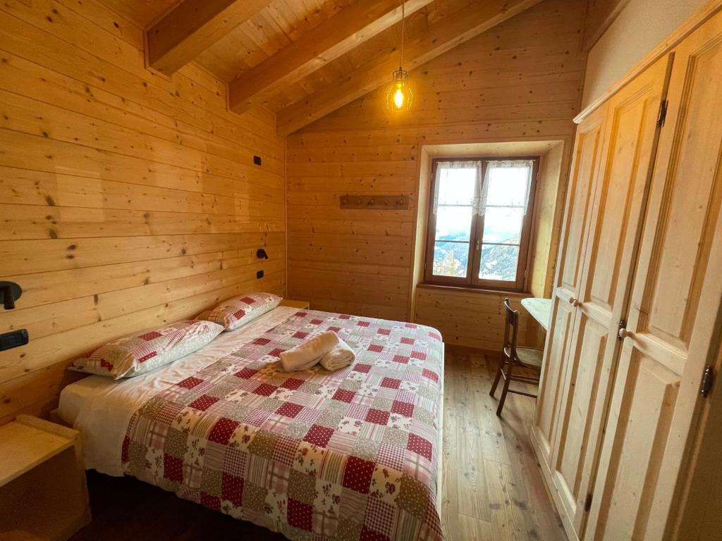 a bedroom with a bed in a wooden cabin at Rifugio Zoia in Chiesa in Valmalenco