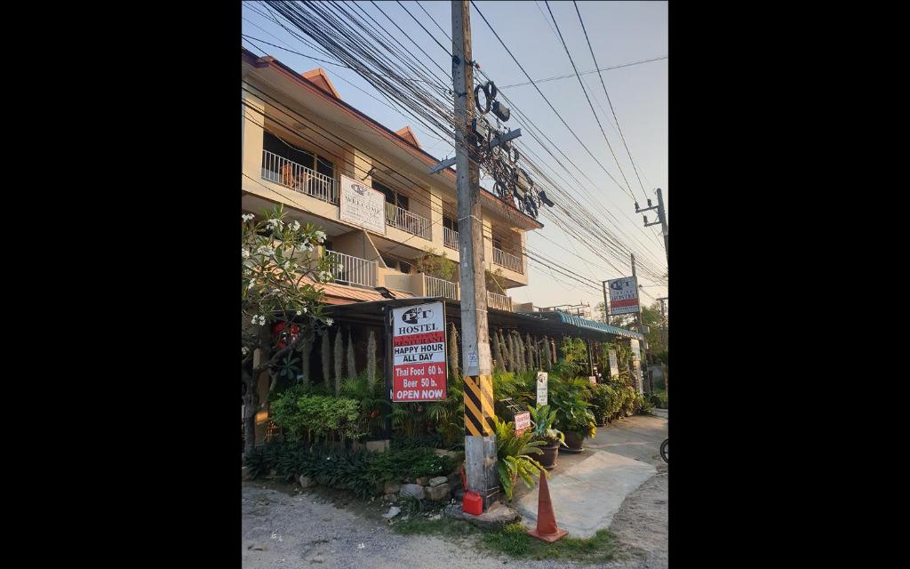 een gebouw met een bord aan de straatkant bij P & T Hostel in Bangrak Beach