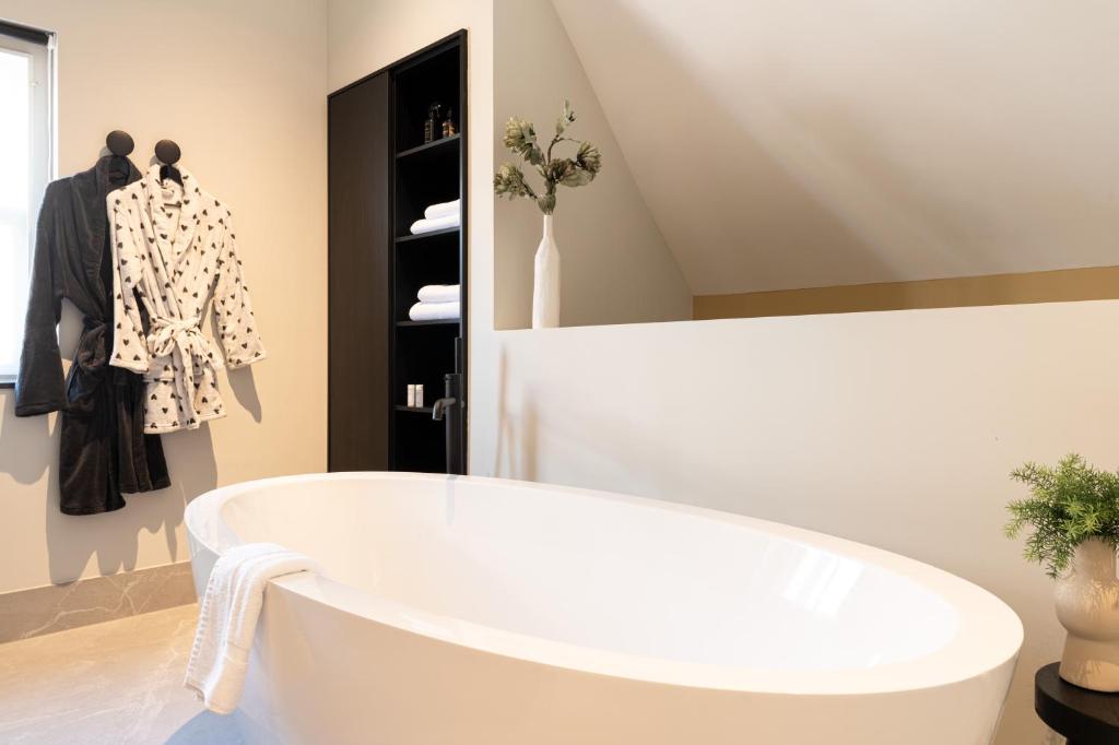 een wit bad in een kamer met wasrekken bij Boutiquehotel Princenjagt in Middelburg