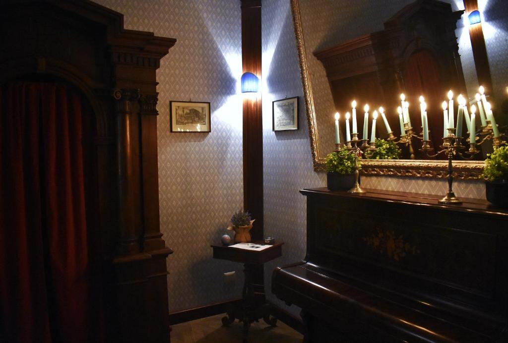 Habitación con piano y espejo con velas encendidas en Il Confessionale, en Castelnuovo di Porto