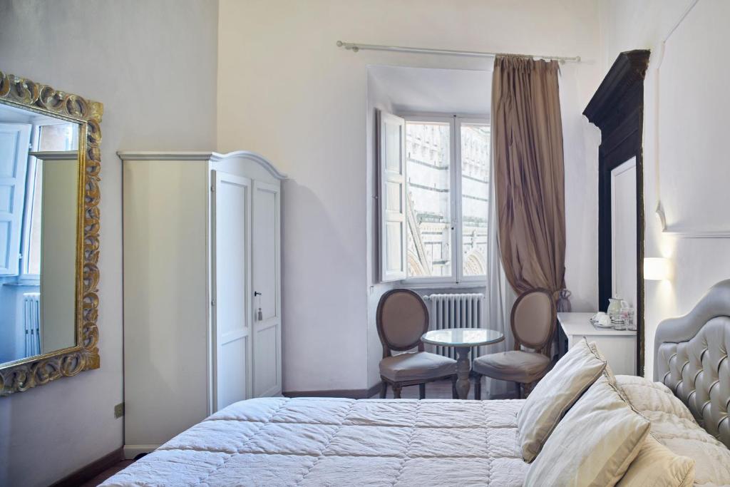 een slaapkamer met een bed en een tafel en stoelen bij Palazzo del Magnifico B&B in Siena