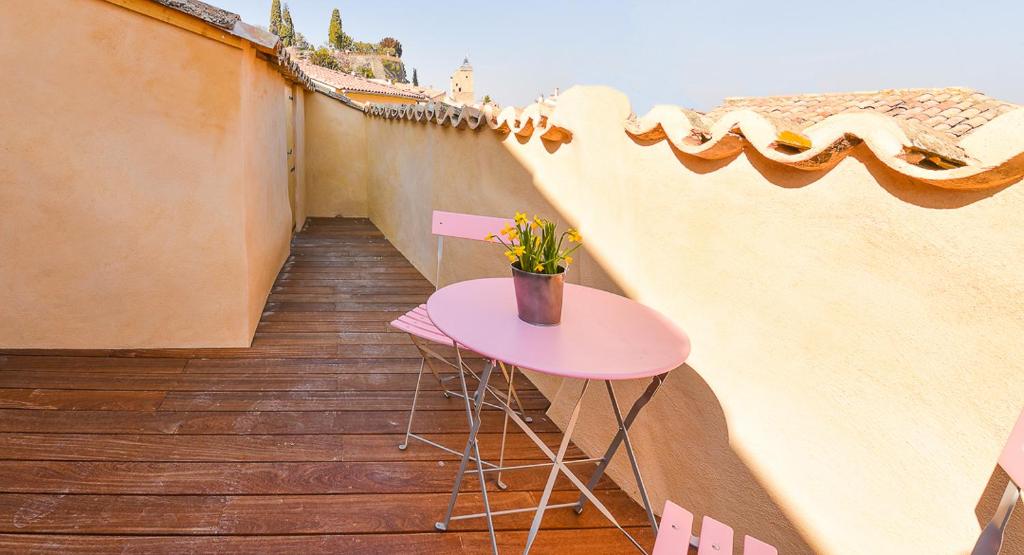 een kleine tafel op een balkon met een roze tafel bij Maison de village Malaucène Ventoux in Malaucène