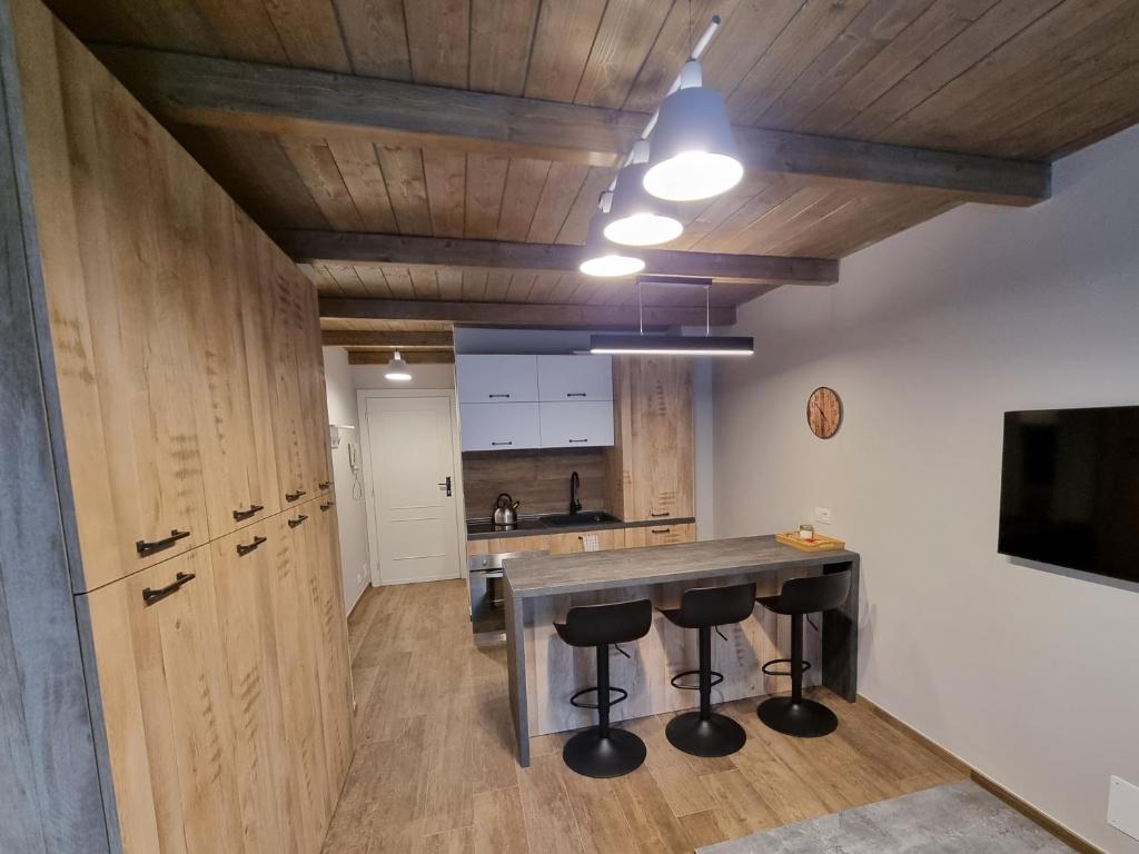 una cucina con soffitti in legno e un bar con sgabelli di Moda Apartments 38 a Sestriere