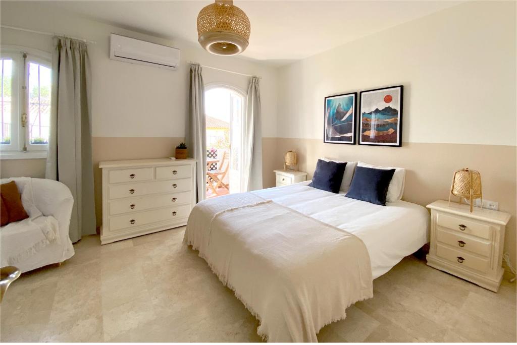 een slaapkamer met een groot wit bed met blauwe kussens bij Casa Lena Town House with private garden near the beach in Nerja