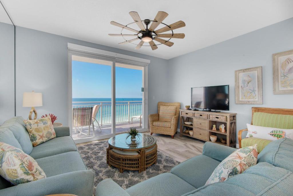 una sala de estar con sofás azules y TV y el océano en Sterling Reef 401, en Panama City Beach