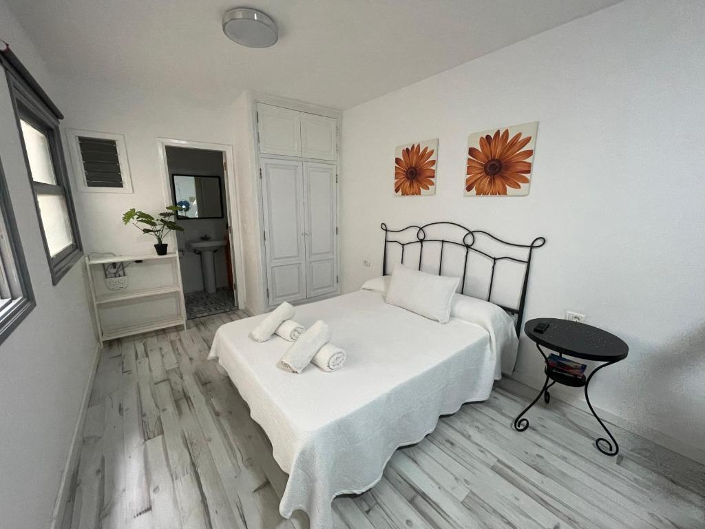 a white bedroom with a bed and a chair at Casa Mora in San Sebastián de la Gomera