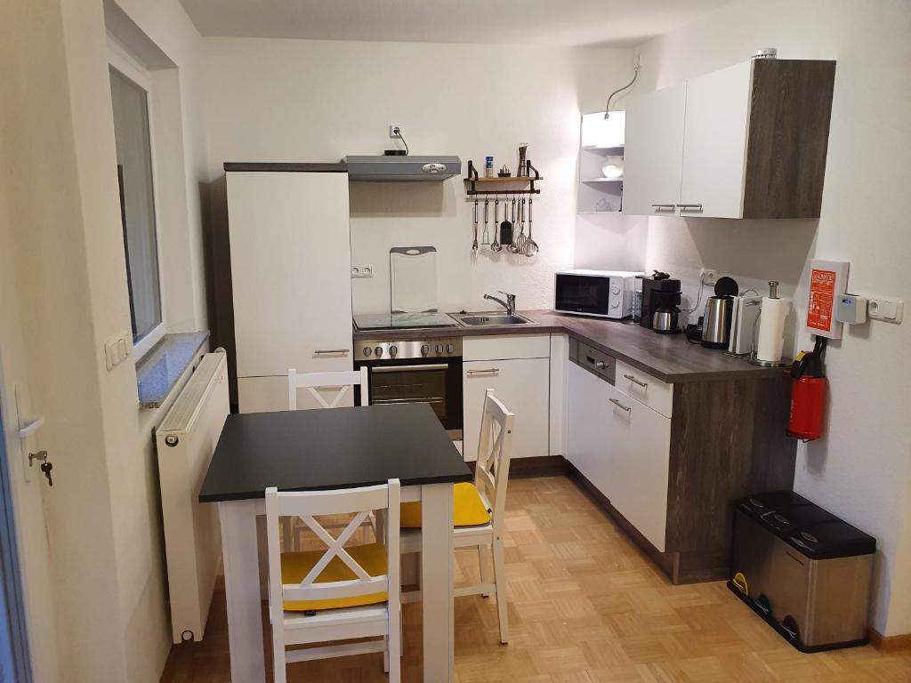 a kitchen with white cabinets and a table and chairs at 37m² 1,5 Zimmer mit Terrasse und super Badezimmer in Tangstedt