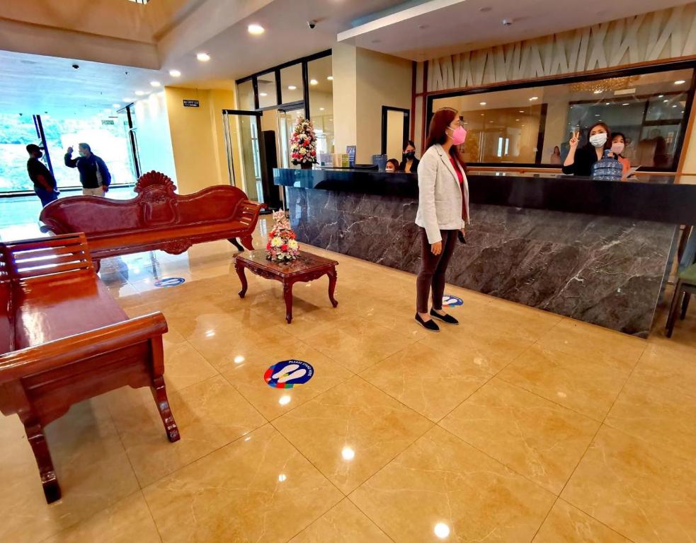 a woman standing in a lobby with a piano at Olive Town Center and Hotel in Baguio