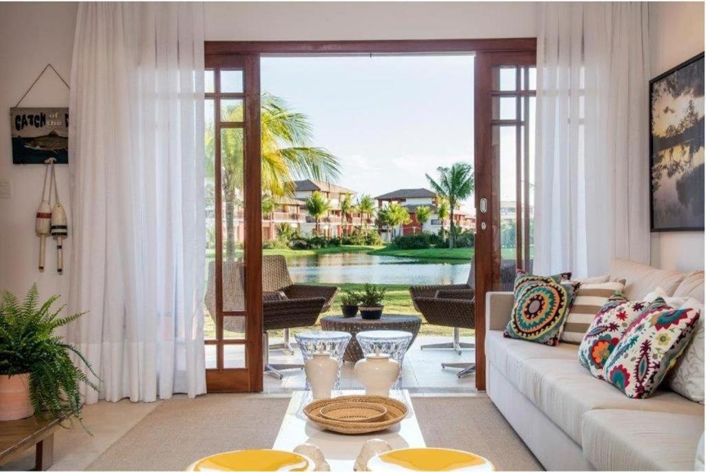 a living room with a couch and a view of a pool at PRAIA DO FORTE - PISCINAS NATURAIS in Praia do Forte